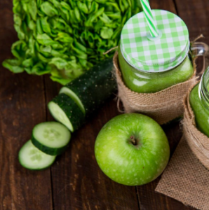 cucumber, green apple, other greens and a green smoothie on a wooden table