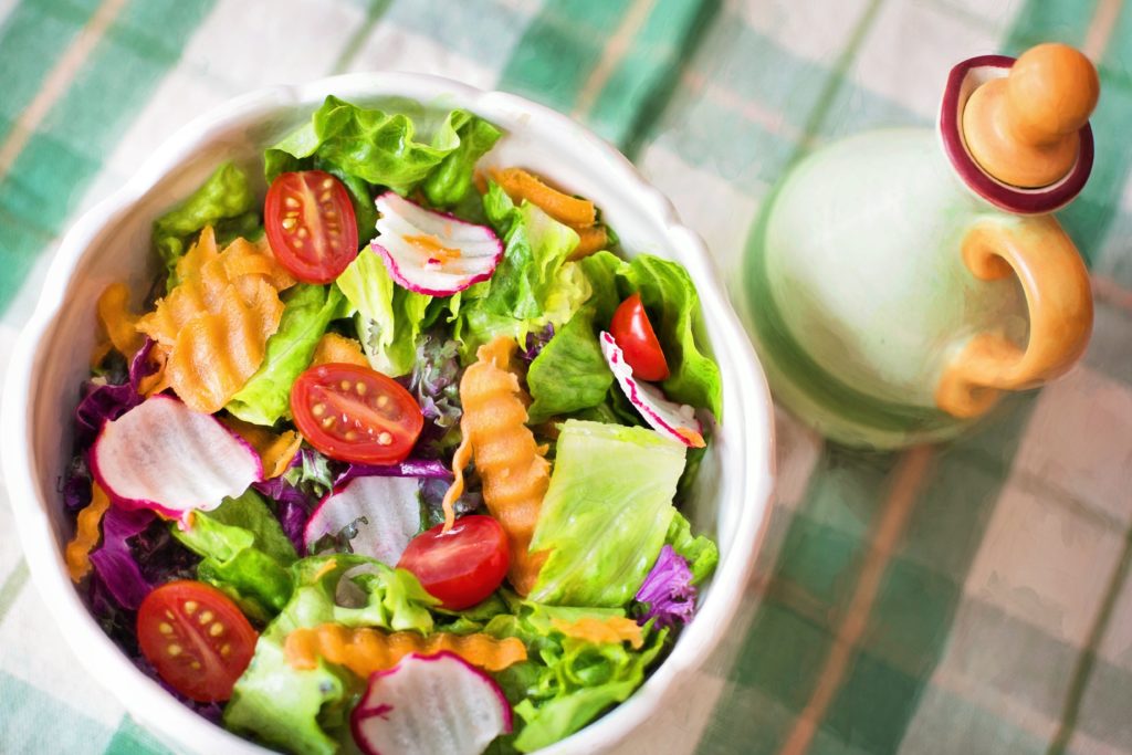 Healthy bowl of salad next to dressing